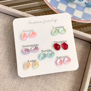 Set of seven pairs of colorful resin stud earrings labeled Monday to Sunday on display card