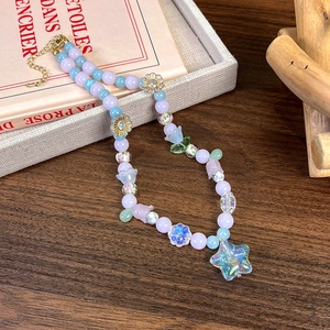 Vue détaillée du collier de perles colorées avec pendentif étoile sur livre vintage