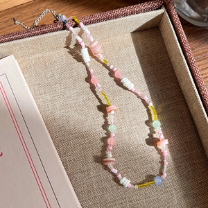 Vue détaillée du collier de perles colorées avec breloques fleurs sur plateau