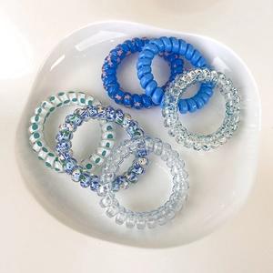 Dettaglio di 6 elastici per capelli a spirale con motivi floreali e pois blu estivi