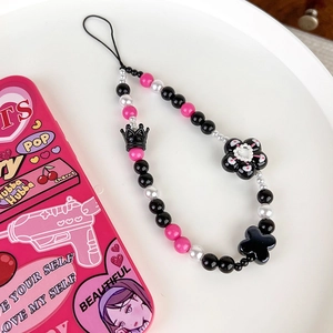 Close-up of Y2K phone strap with black crown and floral beads in a white tray