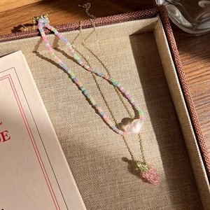 Détail du collier double rang avec perles pastel, cœur et petit pendentif en forme d'ours rose