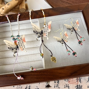 Detail view of ink wash butterfly jewelry set with calligraphy and tassels in a wooden box