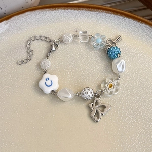 Détail d'un bracelet de perles avec breloques colorées, fleurs souriantes et papillon en métal
