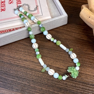 Détails des perles colorées faites à la main et du pendentif feuille verte sur le collier