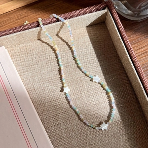 Détail du collier de perles avec pendentifs étoiles dans son coffret à bijoux doublé