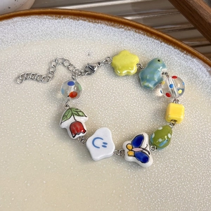 Détail des perles en céramique colorées avec breloques papillon et fleurs sur le bracelet