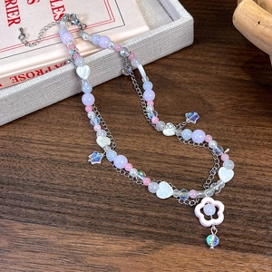 Détail du collier à deux rangs avec perles violettes en forme de cœur et de fleur