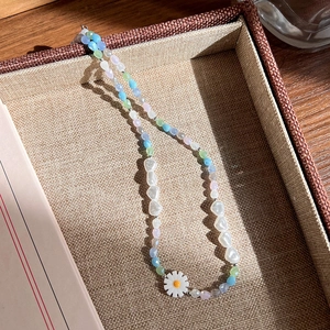 Détail d'un collier de perles colorées avec perles synthétiques et pendentif marguerite
