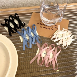 Detail view of lace bow hair clips in black, blue, pink and white on a glass tray