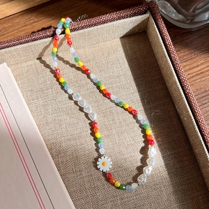 Détail du collier de perles colorées avec pendentif marguerite et perles cœur sur plateau
