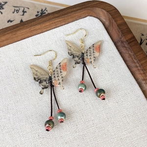 Detail of butterfly earrings with ink landscape painting and red bead tassels