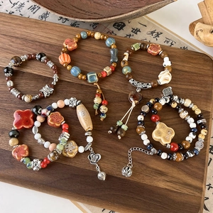 Retro Chinese style ceramic beaded bracelets with lotus charms on a wooden tray