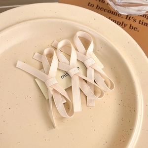 Three beige lace bow hair clips set on a ceramic plate for elegant hair styling