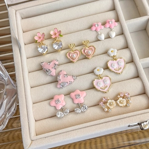Close-up of pink enamel heart and flower earrings with crystals in a jewelry box