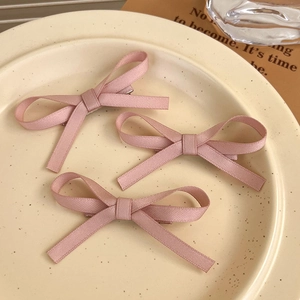 Three pink lace ribbon bow hair clips displayed on a decorative ceramic plate