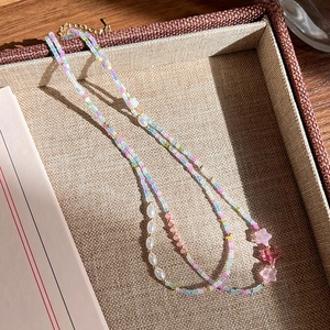 Gros plan du collier perlé avec perles colorées et breloques étoiles roses sur plateau