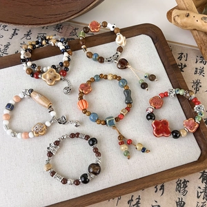 Ethnic style ceramic bead bracelets with vintage pendants on a wooden tray with calligraphy