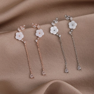Detailed close-up of rose gold and silver flower drop earrings with shell petals and zircon