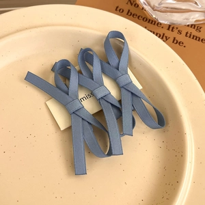 Close-up of three dusty blue lace ribbon bow hair clips on a white display card
