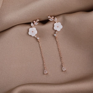 Detail of rose gold flower earrings with shell petals and long chain tassel droplets