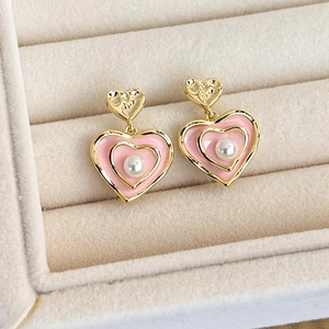 Detail of pink enamel heart earrings with white faux pearls on velvet tray display
