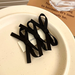 Detailed view of three black lace bow hair clips on a card in a ceramic dish