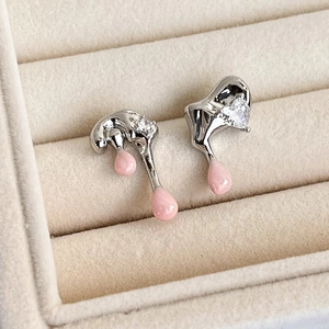 Detailed shot of pink heart earrings with melting silver design on cream velvet tray