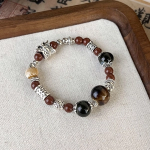 Detail of vintage beaded ceramic bracelet with tiger eye stone and silver metal charms
