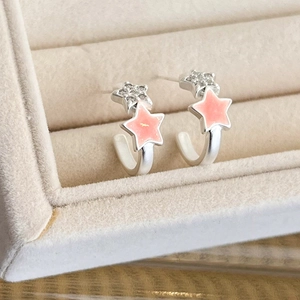 Close-up of pink glitter enamel star earrings with sparkling zircon inlay in beige jewelry box