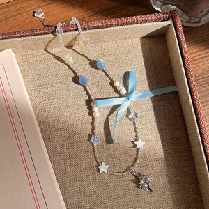 Détail du collier de perles avec pendentif étoile et cristal en forme de coeur
