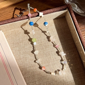 Gros plan d'un collier de perles colorées fait main avec croix sur un plateau à bijoux
