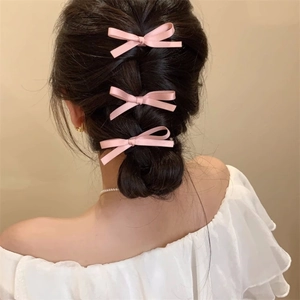 Elegant set of three pink satin bow hair clips styled on a braided princess hairstyle