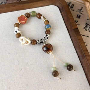 Detail of beaded vintage ceramic bracelet with heart pendant and wooden tassels