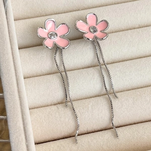 Macro detail of pink enamel flower earrings with sparkling zircon and long silver tassels