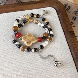 Detail of vintage beaded ceramic bracelet with floral charms and Zen style elements