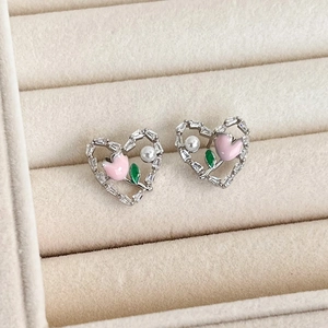 Detail of heart earrings with pink tulip, white pearl, and sparkling zircons in a jewelry box