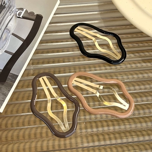 Gros plan de barrettes à cheveux en forme de nuage, noir, marron et beige sur verre