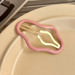 Macro d'une pince à cheveux rose en forme de nuage sur une assiette en céramique beige