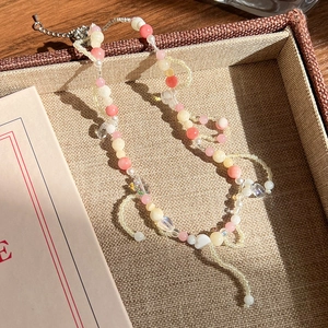 Gros plan d'un collier de perles bohème rose et beige dans un plateau de présentation
