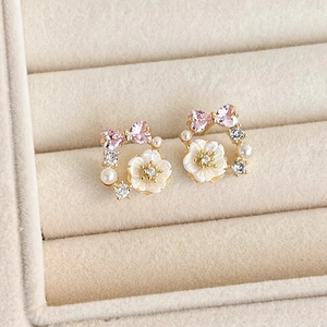 Detailed macro view of pink heart stone and shell flower earrings in a cream velvet box