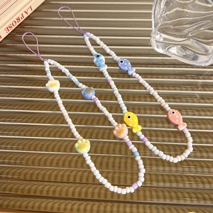 Chic ceramic cat paw and fish beaded phone charms in pastel colors on glass background