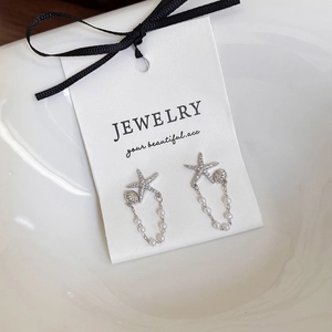 Détail de boucles d'oreilles étoile de mer avec zircons brillants et chaîne de perles