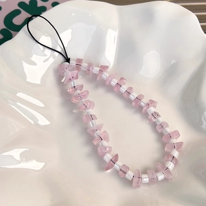 Dettaglio macro del laccetto per telefono con pietre di quarzo rosa e perline bianche