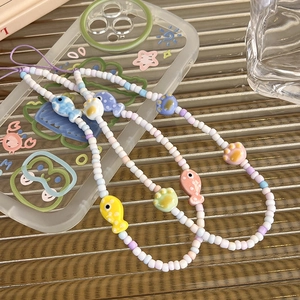 Detail view of colorful macaron beaded phone charm with ceramic fish and cat paw pendants