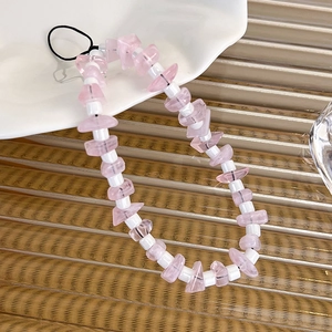 Dettaglio di schegge di cristallo rosa e perle bianche su un cinturino per cellulare