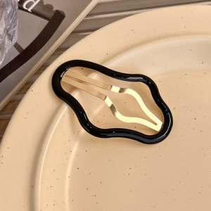 Détail de la barrette à cheveux BB en forme de vague avec cadre noir et ressort doré poli