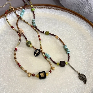 Bohemian beaded necklace with green leaf charms and vintage ethnic style layered on a tray