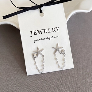 Détail de boucles d'oreilles étoile de mer et coquillage avec zircons et perles