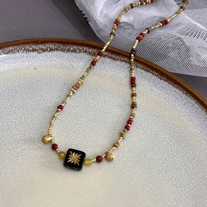 Vintage boho necklace featuring colorful beads and a black square starburst pendant